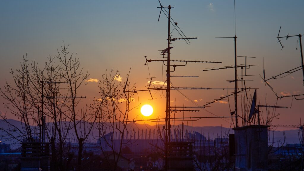 The outline of electricity poles and antennas at dusk.